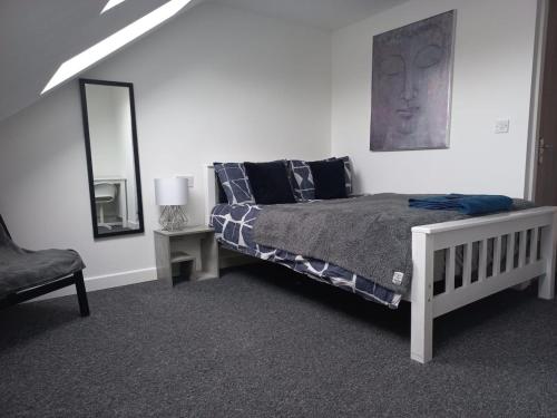 a bedroom with a bed and a mirror and a chair at Large 6 Bed 6 Bathroom House - Ideal For Families, Large Groups, Contractors & Business Travellers in Watford