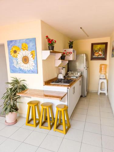 a kitchen with yellow stools and a counter and a refrigerator at Esquina del Pintor in Guadalajara