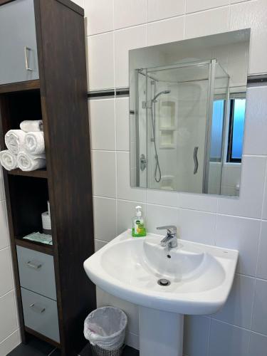 a white bathroom with a sink and a mirror at Waterfront studio unit near Auckland Airport in Auckland