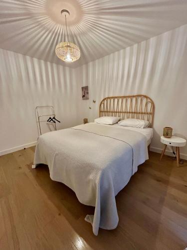 une chambre avec un grand lit blanc avec un lustre dans l'établissement La terrasse de Deauville, à Deauville