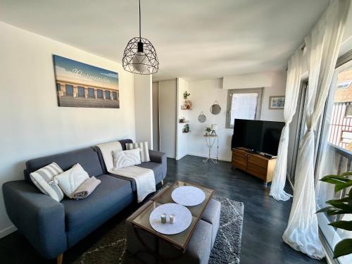 a living room with a blue couch and a tv at Un été sans fin à Deauville in Deauville