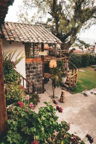 una pequeña casa con un árbol y una valla en Casa de Mariano, en Otavalo