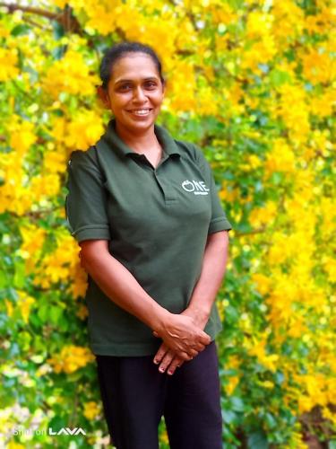 a woman in a green shirt standing in front of yellow flowers at AT ONE - with Nature Glamping Resort in Rekawa