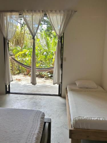 a bedroom with two beds and a door to a garden at Pachamama Tropical Garden Lodge in Carmen