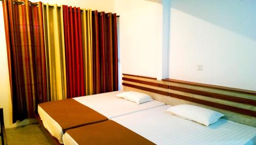 a bedroom with two beds in front of a window at Pelican View Cottages in Kataragama