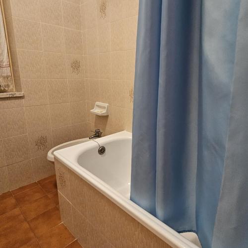 a bathroom with a tub with a blue shower curtain at La stella sulle terrazze in Zoagli