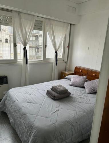 a bedroom with a large bed with two windows at Cómodo y excelente ubicación in Mar del Plata