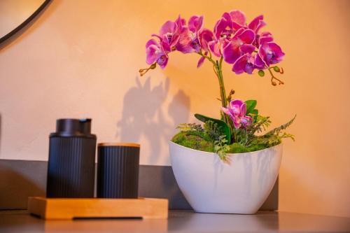 a white vase with purple flowers on a table at Tierra Mistú in Ginebra