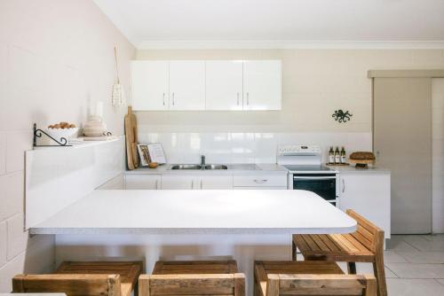 Merduka Sands 4 - Cozy charming cottage في Brooms Head: مطبخ بدولاب بيضاء وقمة بيضاء
