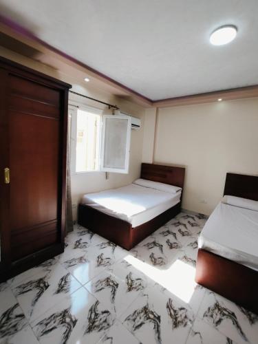 a small bedroom with two beds and a window at غرف و استديوهات منفصلة مفروش غرفة ماستر بحمام ومطبخ صغير لا يتشارك مع الغير اي شيء بنات فقط أو عوائل in 6th Of October
