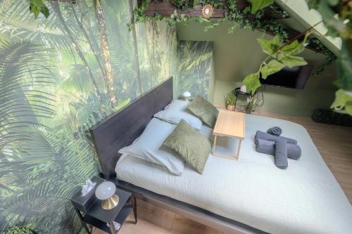 a bedroom with a bed with white pillows and a plant at La Suite Jungle - High Tech - NETFLIX - WIFI très Haut Débit in Vertou