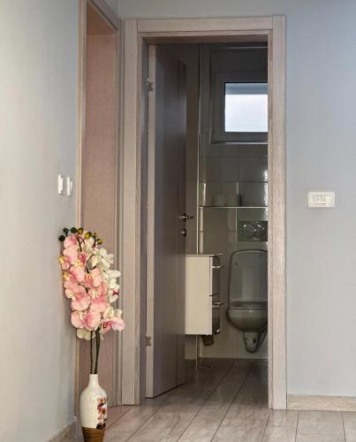 a bathroom with a toilet and a vase of flowers at Paradise beachfront view 1 in Bar