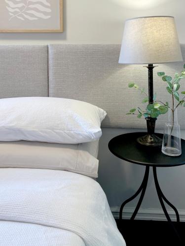 a bed with a table with a lamp on it at Stylish Executive City Pad w Parking and Pool in Perth