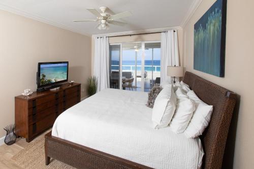 ein Schlafzimmer mit einem weißen Bett und einem Fernseher in der Unterkunft South Bay Beach Club #28 - 3Bedroom 2 Bathroom Unit in George Town