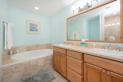 ein Badezimmer mit 2 Waschbecken, einer Badewanne und einem Spiegel in der Unterkunft South Bay Beach Club #30 - 3 Bedroom 2 Bathroom Unit in George Town