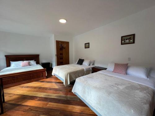 Un dormitorio con dos camas y suelo de madera. en Villa Pastaza 4 Bedroom 3 Bath, en Baños