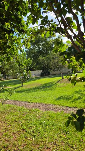 a grassy field with trees and a path at El Jardín Secreto in Trinidad