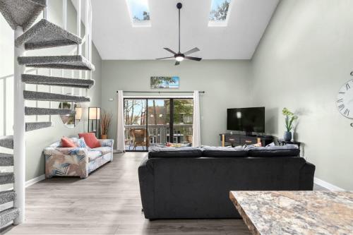 a living room with a black couch and a staircase at 33H-Golf Colony in Surfside in Myrtle Beach