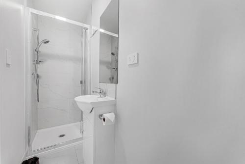 a white bathroom with a shower and a sink at Onehunga Suites in Auckland