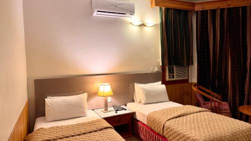 a hotel room with two beds and a lamp at Rock City Resort in Mingora