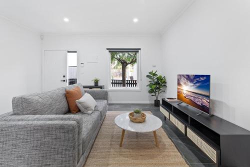 a living room with a couch and a tv at Sleek 2-Bed Terrace near Local Parks in Melbourne