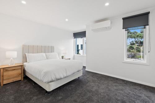 a white bedroom with a bed and a window at Sleek 2-Bed Terrace near Local Parks in Melbourne
