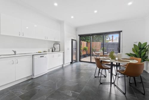 a kitchen and dining room with a table and chairs at Sleek 2-Bed Terrace near Local Parks in Melbourne