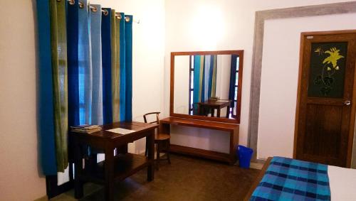 a bedroom with a desk and a mirror and a bed at Pelican View Cottages in Kataragama