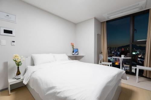 a white bedroom with a large white bed and a window at 벨라 레지던스 in Chuncheon
