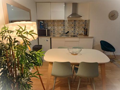 une cuisine avec une table et des chaises blanches ainsi qu'une table dans l'établissement Paris & Disney - LES BORDS DE MARNE, à Meaux