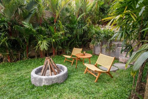 a yard with two chairs and a table and a fire pit at Aura Svarga - Swarga House in Selat