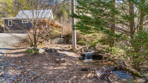 a cabin in the woods with a pond and trees at Serenade Collection by Carolina Mornings in Hendersonville