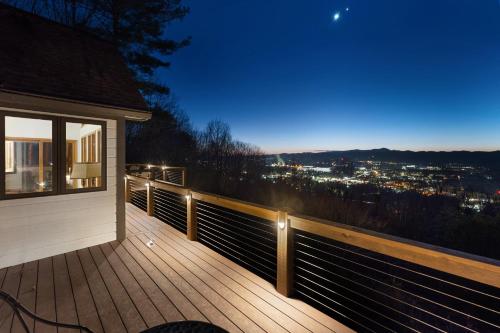 a deck with a view of a city at night at Sunset Peaks by Carolina Mornings in Asheville