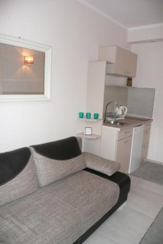 a living room with a couch and a kitchen at Pensjonat Landrynka in Darłówko
