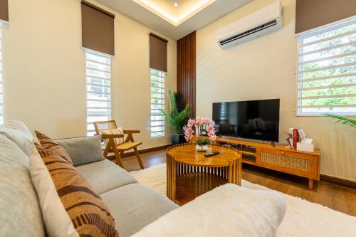 a living room with a couch and a tv at La Ferringhi Villa - Tropical Collection, by ALV in Batu Ferringhi