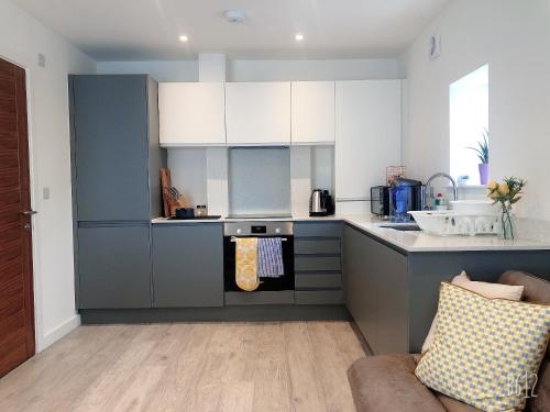 a kitchen with blue and white cabinets and a couch at Cottage House - Preston Village - Preston Park in Brighton & Hove