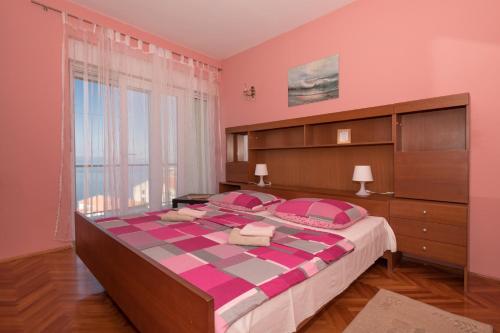 une chambre rose avec un grand lit et une grande fenêtre dans l'établissement Apartments by the sea Podgora, Makarska - 23678, à Podgora