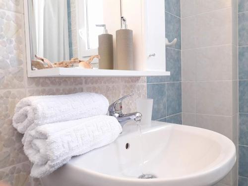 a bathroom with a sink and a mirror and towels at Stavento Apartments in Aliki