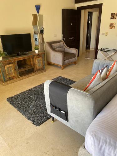 a living room with a couch and a flat screen tv at Cozy studio in Azzurra Resort Sahl Hasheesh 65 Sq M in Hurghada