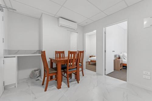 a dining room with a table and chairs and a bedroom at Onehunga Suites in Auckland