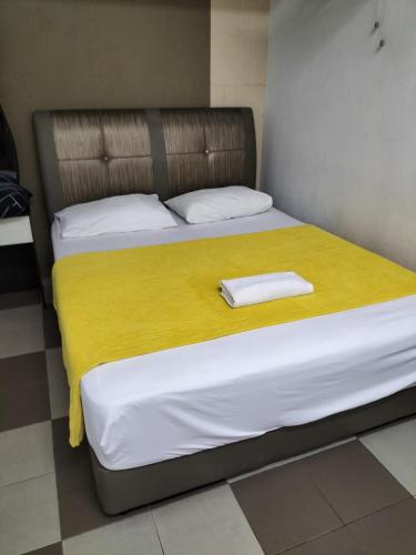 two beds in a room with a yellow blanket at Ulfah Hotel in Mersing