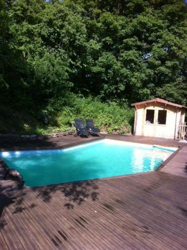 a swimming pool with two chairs on a wooden deck at Loft "Home, Sauna & Pool" in Osenbach