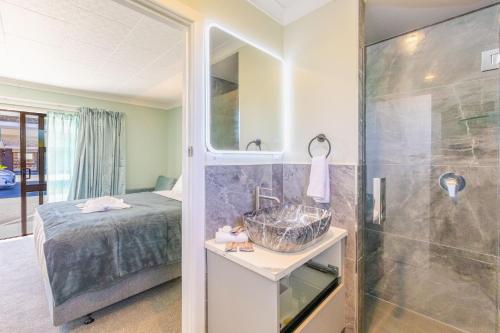 a bathroom with a bed and a sink and a shower at Lavana Motel in Hastings