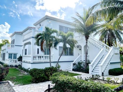 a white house with palm trees in front of it at The Seagate in The Bight Settlements