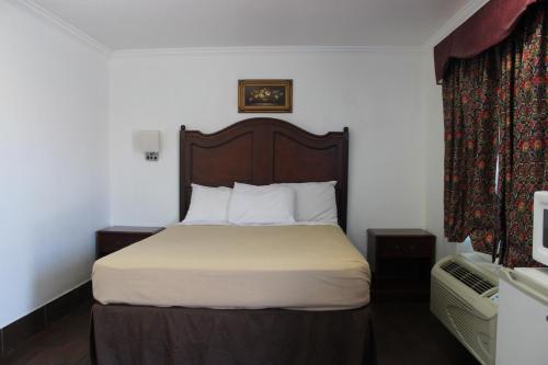 a bedroom with a bed with a wooden headboard at City Center Motel Indio in Indio