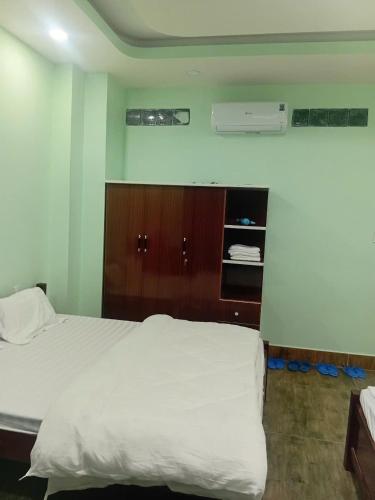 a bedroom with a white bed and a wooden cabinet at HOTEL MOTeL ĐỒNG KHỞI in Ben Tre