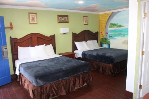 a hotel room with two beds and a painting on the wall at City Center Motel Indio in Indio