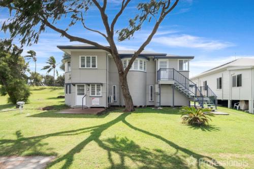 a large house with a tree in the yard at The Castaway in Emu Park