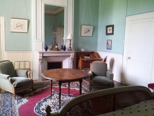 a living room with a table and chairs and a fireplace at Chambres d'hôtes & Gîtes du Château de Grand Rullecourt in Grand Rullecourt