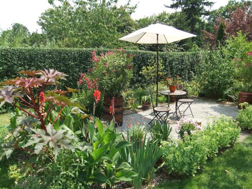 a patio with a table and an umbrella in a garden at Słoneczne apartamenty in Sobótka